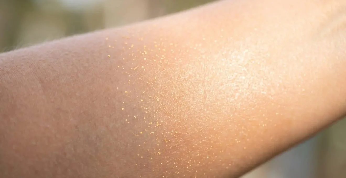 Gros plan d'une peau lumineuse avec particules dorées symbolisant les peptides de collagène.